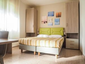 卡奥莱安杰洛酒店的一间卧室配有一张带绿色床头板的床