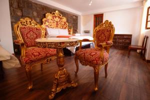 库斯科Hotel Monasterio del Inka的一间设有两把椅子、一张桌子和一张床的房间