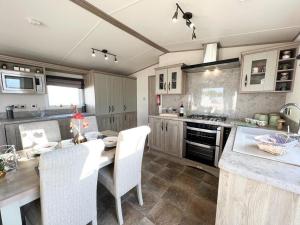 斯凯格内斯Stunning Caravan With Full Lake View At Southview Holiday Park Ref 33004ml的一间带桌椅的厨房和一间带炉灶的厨房
