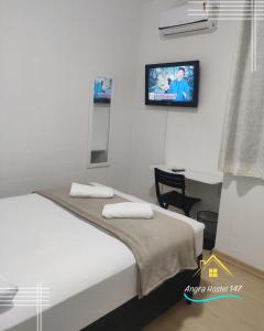安格拉杜斯雷斯Angra Hostel 147的卧室配有一张床,墙上配有电视。