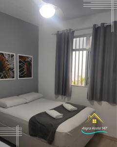 安格拉杜斯雷斯Angra Hostel 147的一间卧室设有一张大床和窗户