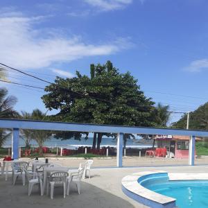 皮乌马Cobertura vista para o mar e piscina的一个带白色椅子、桌子和树的游泳池