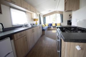 亨斯坦顿Caravan With Decking Within Walking Distance To Hunstanton Beach Ref 23054s的厨房配有水槽和炉灶 顶部烤箱