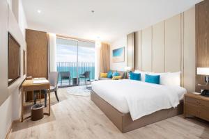 芽庄Homie Panorama Beachfront Residences Nha Trang的酒店客房设有一张大床和一张书桌。