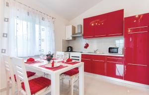 普拉Lovely Home In Pula With Wifi的厨房配有红色橱柜和白色的桌椅