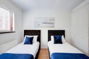 彼得伯勒Great Location Free Parking Contractor Leisure的白色客房的两张床,配有蓝色枕头