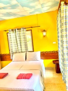 涛岛苏梅岛热带度假酒店的黄色卧室,配有带两个红色枕头的床