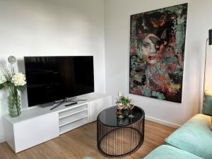 腓特烈港Ferienwohnung Bodenseeglück的白色的客厅配有电视和桌子
