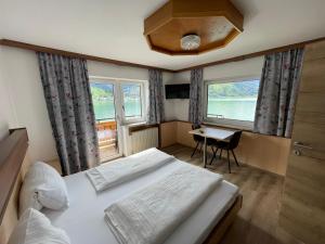 滨湖采尔Hotel-Garni Seestrand的一间卧室配有一张床、一张书桌和两个窗户。
