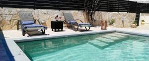 KatomérionVilla Iliogioma with private pool and sea view的一个带两把椅子、一张桌子和一张桌子的游泳池