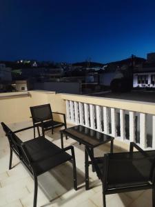 卡尔帕索斯Captain's Mermaid Houses, Karpathos的阳台配有3把椅子和1张桌子