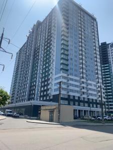 敖德萨Sky apartments Budova的一座高大的建筑,前面有汽车停放