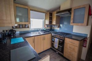 滨海克拉克顿8 Berth Caravan For Hire Near Clacton-on-sea In Essex Ref 26287e的厨房配有木制橱柜和炉灶烤箱。