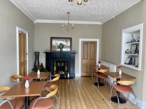 利文-法夫Lomond Guest House的一间带桌椅和壁炉的用餐室