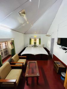 马迪凯里Coorg Daffodil Guesthouse的一间卧室配有一张床、一张沙发和一张桌子