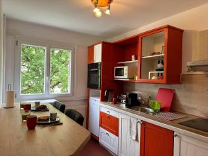 安纳马斯Royale London Signature * * * * *的厨房配有红色橱柜和木桌