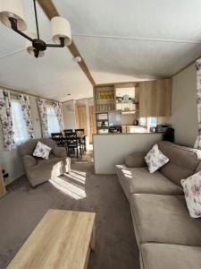 古德瑞同3 bed luxury lodge at Hoburne Devon Bay的带沙发和桌子的客厅以及厨房。
