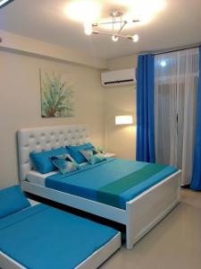 宿务Condo Near Mactan Airport的一间卧室配有一张带蓝色床单和蓝色窗帘的床。