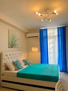 宿务Condo Near Mactan Airport的一间卧室配有一张带蓝色窗帘的床和一扇窗户