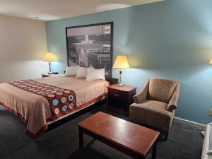 Moodybudgetel Inn & Suites的配有一张床和一把椅子的酒店客房
