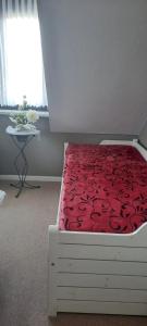 维斯马Ferienhaus in der Hansestadt mit Blick auf Ostsee的一间卧室配有一张带红色棉被的床和一张桌子