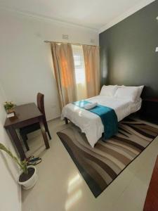 卢萨卡Busisiwe's RM Home的一间卧室配有一张床、一张桌子和盆栽植物