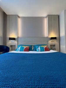 贝诺代Le Cornouaille Hotel & Spa的一间卧室配有一张大床,提供蓝色的床单和枕头