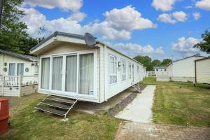 滨海克拉克顿Modern 6 Berth Caravan At Highfield Grange In Essex Ref 26609p的院子内带椅子的白色小房子