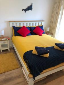 布德Bosun's Bude的一间卧室配有一张带红色和蓝色枕头的大床