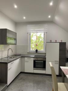 波斯托伊纳Apartma Azurre的厨房配有白色橱柜、水槽和窗户。