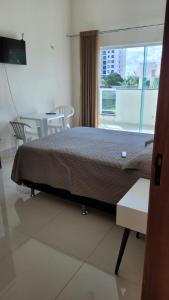 帕尔马斯Orla Graciosa的一间卧室配有一张床、一张桌子和一个窗户。