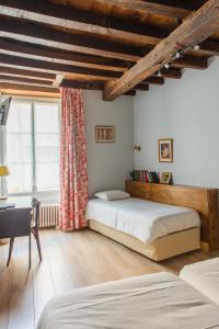博让西Le Relais Des Templiers的一间卧室设有两张床、一张桌子和一个窗口。