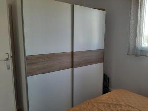 沃迪切Apartman-Kuzminski-Kraje14的卧室配有白色橱柜和1张床。