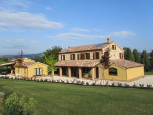 Castelbellino拉维奇亚丰堤农庄酒店的一座带绿色草坪的大型黄色房屋