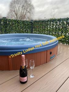 塔特舍尔Trinity lodge hot tub escapes at Tattershall lakes的一瓶香槟和热水浴缸旁的一杯