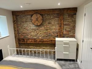NewboldChatsworth stables的一间卧室,墙上有砖墙,上面有时钟
