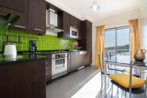 楼尔Apartamento Mãe Soberana的厨房配有棕色橱柜和绿色瓷砖墙