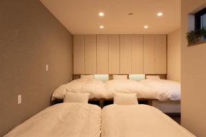 高山KAjette的配有白色床单的客房内的两张床