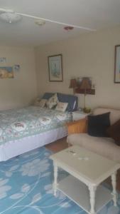 韦斯特利Cozy, cute beach condo in Westerly RI . Best value in Westerly!!的一间卧室配有一张床、一张桌子和一张沙发