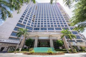 深圳深圳湾科技园丽雅查尔顿酒店的一座高大的建筑,前面有棕榈树