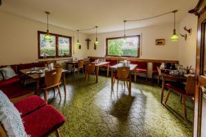 米滕瓦尔德多灵酒店的用餐室配有桌子和红色椅子