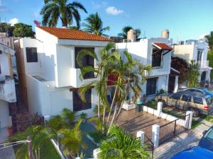 坎昆Cómoda casa céntrica con alberca privada en Cancún的一座棕榈树掩映的白色房子
