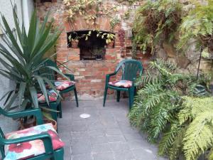 霍巴特Josie's Cottage的两把绿色椅子坐在砖墙旁边,墙上有植物
