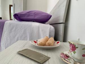 多尔加利Agriturismo La Croisette的一张桌子,上面放着一碗饼干,床上放着一杯