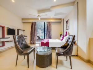 卡兰古特Grandeur De Sanchi- Luxury Beach Resort & Spa的一间卧室配有一张床、两把椅子和一张桌子
