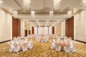 青浦上海夏阳湖皇冠假日酒店 的一个带白色桌子和白色椅子的大型宴会厅