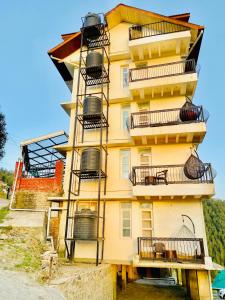 西姆拉Staynest Mashobra with balcony- A peacefull stay的黄色的建筑,旁边设有阳台