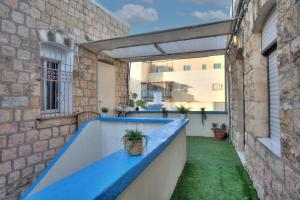 萨法德בראשית - סוויטות בוטיק בצפת העתיקה - Beresheet - Boutique Suites in the Old City的一个带蓝色长椅和大楼的户外阳台