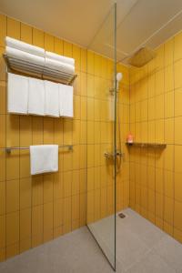 马尼拉lyf Malate Manila - Managed by The Ascott Limited的黄色瓷砖浴室设有淋浴和毛巾