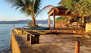 帕拉蒂REFUGIO na frente do mar em Ilha de Araujo的水边有长凳和船的房子